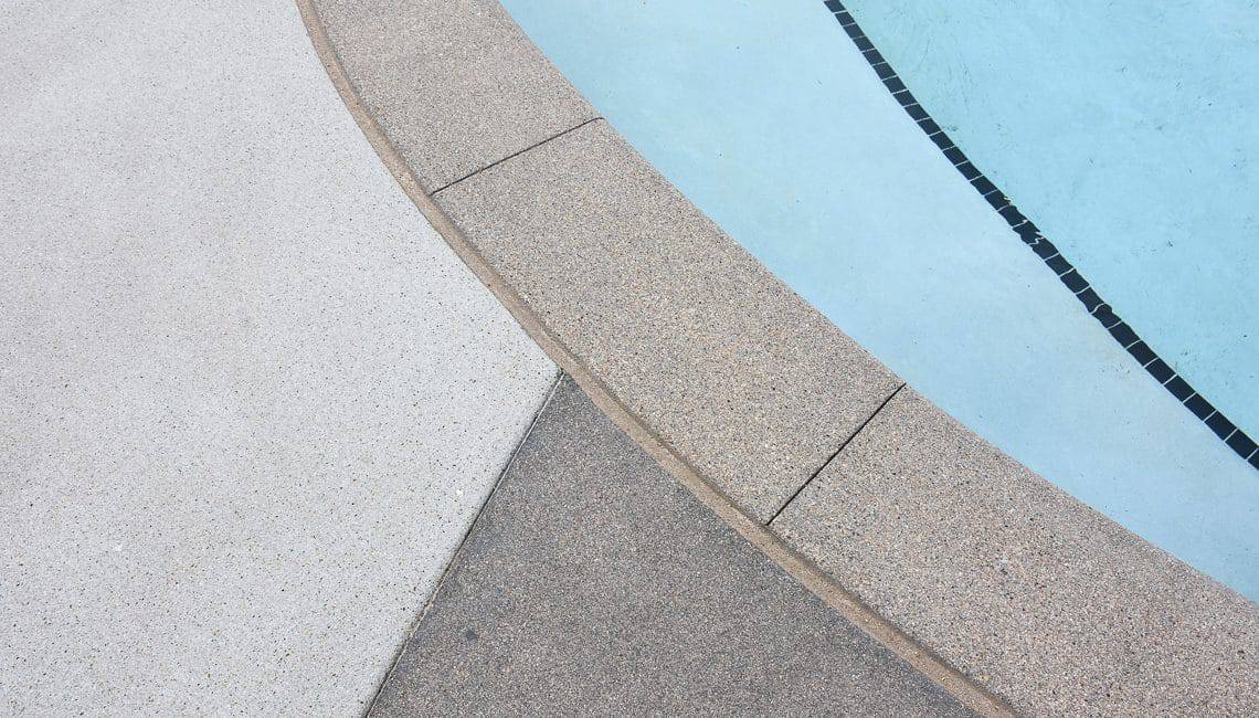 Up close perspective of Sandscape Refined coping and pool deck at apartment complex.