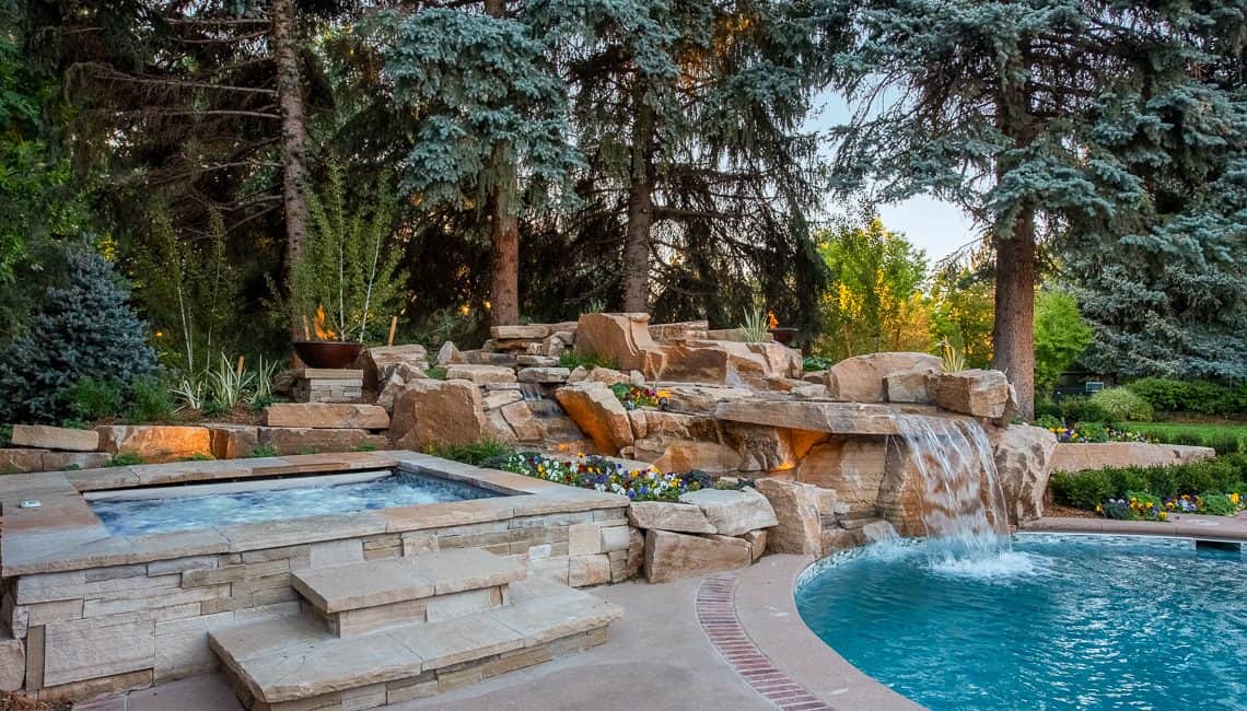Dream backyard at private residence with RGB lighting in spa and sandstone waterfall.